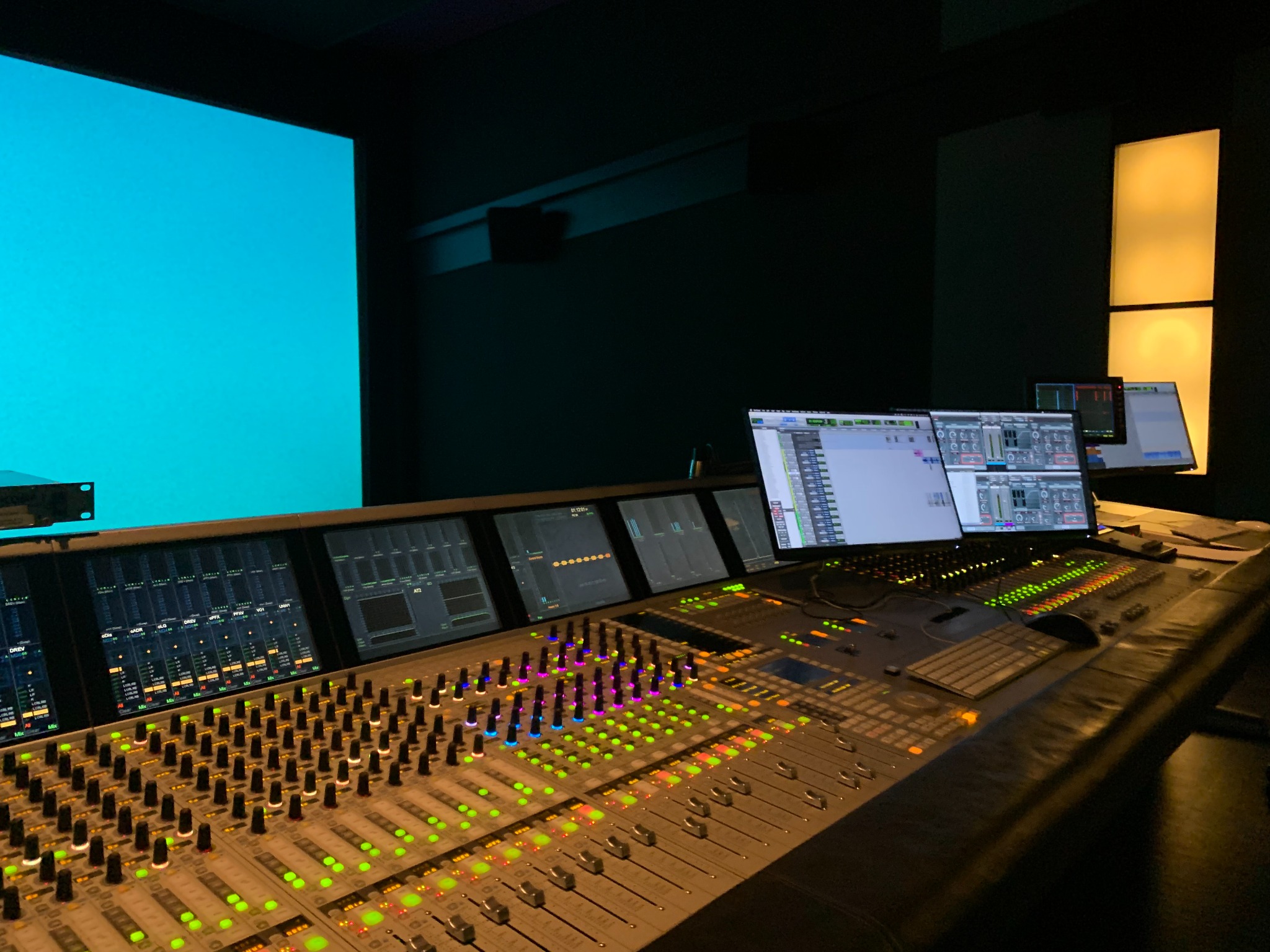 Mixing console and blue SENECA screen in a post-production studio